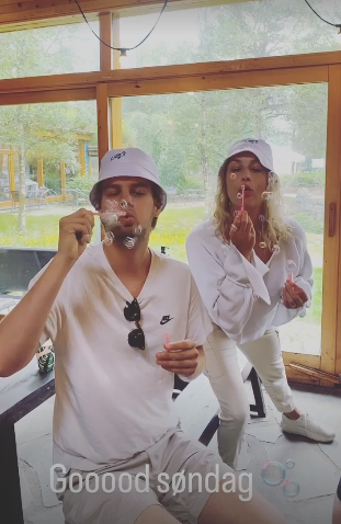 To personer som er kledd i hvitt og blåser såpebobler med tekst Goooood søndag